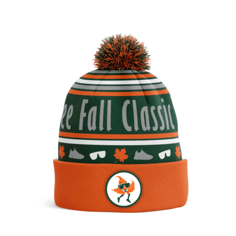 An orange and green pom pom hat with Free Fall Classic, leaves, and sneakers knitted into the design. 